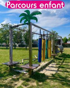 a playground in a park with a palm tree on it at Grand mobil home exposé sud, 2 salles de bain in Onzain