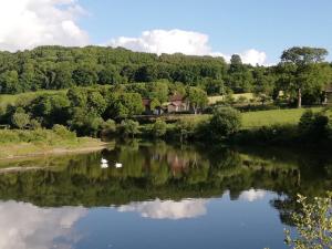 a river with a reflection of a house in the water at Locksters lodges in Hereford