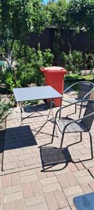einen Tisch und zwei Stühle und einen roten Mülleimer in der Unterkunft Elmarkos in Kolonia Chwaszczyńska