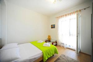 1 dormitorio con 1 cama con manta verde y ventana en Apartman Marin-Dalmatian way of vacation, en Gornje Selo