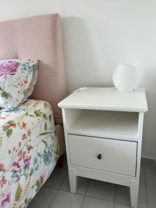 uma mesa de cabeceira branca ao lado de uma cama com uma gaveta em Casa caretta caretta em Manfredónia