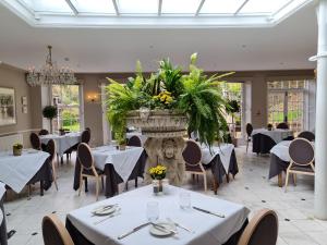 a dining room with tables and a large pot of flowers at Powdermills Country House Hotel in Battle