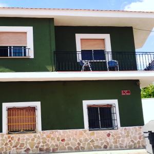 um edifício verde com duas janelas e duas cadeiras numa varanda em El Refugio Bed & Breakfast em Villarrobledo