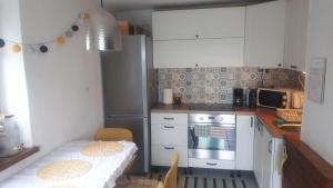 a small kitchen with white cabinets and a table in it at Domek z widokiem na jezioro Rożnowskie 