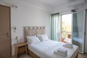 een slaapkamer met een bed met witte lakens en een raam bij Annis House in Skiathos-stad