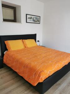 a bed with an orange comforter in a bedroom at La casa de Nani in Porcen