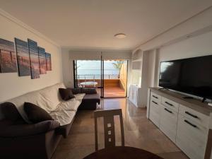 Una sala de estar con un sofá y un televisor de pantalla plana. en exclusiva primera línea de playa, en Aguadulce