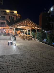 a wooden pavilion with tables and benches at night at Хотел CANAVAN'S - beach in 2 minutes, free parking and WiFi in Ravda