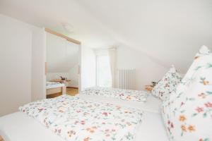 a white bedroom with a bed and pillows at Ferienwohnung Menzer am See in Öhningen