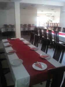 a long table with red and white plates and chairs at Guest House Ostojić in Međugorje