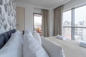 a bedroom with a bed with white pillows and a window at Holysuite Savyon View Tower in Jerusalem