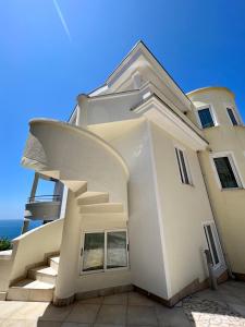 a white house with stairs and the ocean in the background at Apartments Amina in Ulcinj