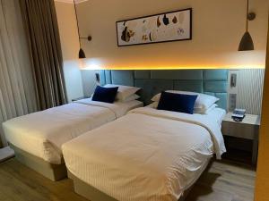 2 camas en una habitación de hotel con sábanas blancas y almohadas azules en فندق رؤيا الاندلس النخبة - Roaya Alandalus Elite Hotel, en Medina