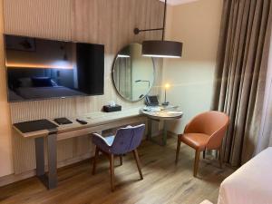 a hotel room with a desk and a mirror at Roya Al Andalus Hotel in Al Madinah