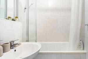 a white bathroom with a sink and a shower at Cozy Apt in Central London in London