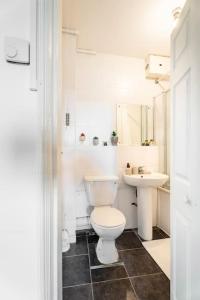 a white bathroom with a toilet and a sink at Cozy Apt in Central London in London