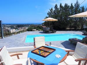 einen Tisch und Stühle neben einem Pool in der Unterkunft Villa Aurora Dome in Afandou