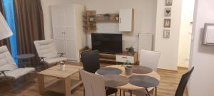 sala de estar con mesa y TV en Hama Fresh Garden Wellness Apartman, en Siófok