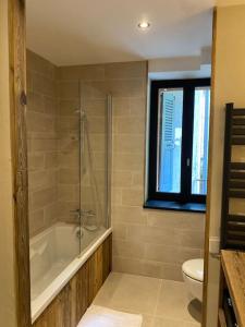 ein Bad mit einer Badewanne, einem WC und einem Fenster in der Unterkunft Appartement Saint-Gervais-Les-Bains in Saint-Gervais-les-Bains