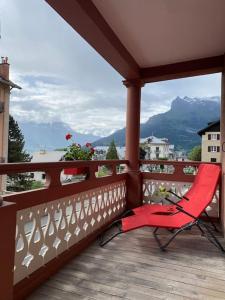 una silla roja en el balcón con vistas a las montañas en Appartement Saint-Gervais-Les-Bains, en Saint-Gervais-les-Bains