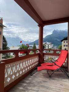 a red chair on a balcony with a view of mountains at Appartement Saint-Gervais-Les-Bains in Saint-Gervais-les-Bains