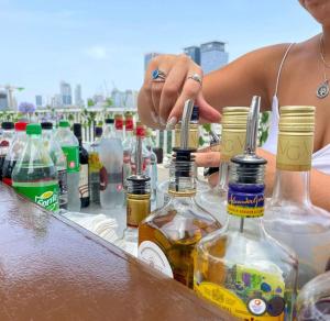 a woman is standing next to a table with bottles of alcohol at Gia Dormitory in Tel Aviv