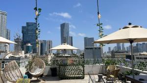 a patio with chairs and umbrellas and a city skyline at Gia Dormitory in Tel Aviv