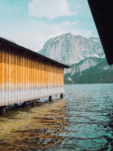 un edificio sobre un cuerpo de agua con una montaña en SIEGLGUT, en Altaussee