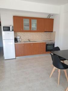 cocina con armarios de madera, mesa y nevera en Konstantinos Apartmend Halkidiki, en Sozopoli