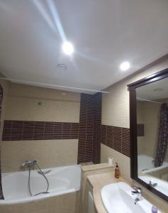 ein Badezimmer mit einer Badewanne, einem Waschbecken und einem Spiegel in der Unterkunft Confort Inn Lac 2 in Tunis