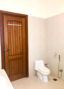 a bathroom with a toilet and a wooden door at Royal Palace Boutique Hotel in Islamabad