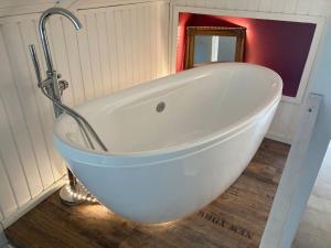 a white bath tub in a bathroom with a mirror at Behagliches Nurdachhaus im Ferienhausgebiet in Langelsheim