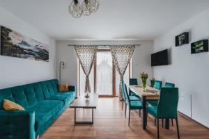ein Wohnzimmer mit einem grünen Sofa und einem Tisch in der Unterkunft Gorczański Resort Domek w Górach Sauna Jacuzzi in Nowy Targ