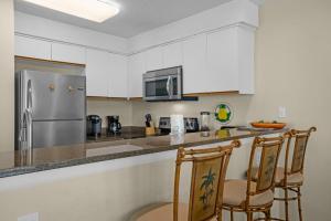 a kitchen with white cabinets and a stainless steel refrigerator at The Palms #601 in Fort Walton Beach