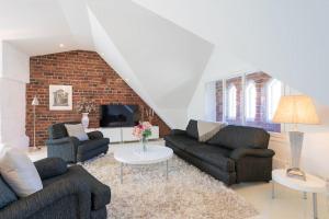 a living room with two couches and a brick wall at Stunning Huvilakatu Penthouse in Helsinki