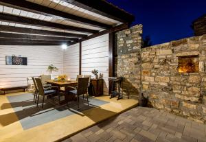 un patio con mesa, sillas y pared de piedra. en CASA MARIO-charming stone house with jacuzzi en Svetvinčenat
