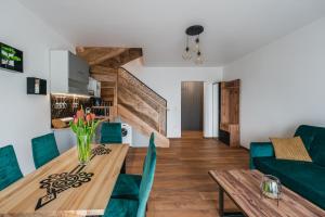 a dining room and living room with a wooden table and green chairs at Gorczański Resort Domek w Górach Sauna Jacuzzi in Nowy Targ