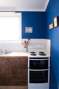 瞭望角的住宿－Hillhouse，厨房配有白色炉灶和蓝色的墙壁