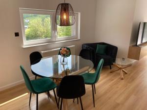 uma sala de estar com uma mesa de vidro e cadeiras verdes em Apartament na Spokojnej em Wisla