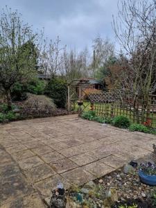 a garden with a stone patio and a fence at Shunters Cottage in Darnick