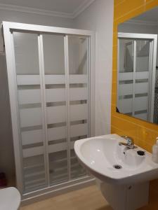 La salle de bains est pourvue d'un lavabo blanc et d'une douche. dans l'établissement Mi piso en la ría, à Barreiros