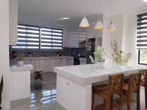 a kitchen with white cabinets and a large island with chairs at Taylors Country Home by Travellers Inn at The Ground in Tangaro