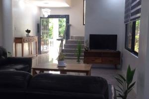 a living room with a couch and a tv at Taylors Country Home by Travellers Inn at The Ground in Tangaro