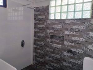 uma casa de banho com uma parede de tijolos e um chuveiro em Taylors Country Home by Travellers Inn at The Ground em Tangaro