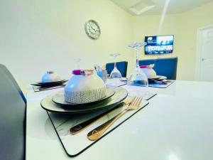 a table with plates and utensils and a clock at Darlington City Flat in Darlington