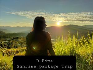 a woman sitting on a hill looking at the sunset at D-Rima Homestay Ruteng in Ruteng