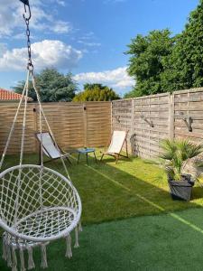 a swing in a yard with two chairs and a fence at Appartement relaxant au bassin in La Teste-de-Buch