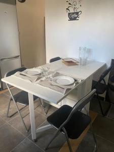 une table blanche avec des chaises et des assiettes dessus dans l'établissement Appartement relaxant au bassin, à La Teste-de-Buch