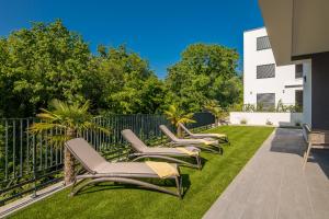 a row of chaise lounge chairs on a lawn at Apartment Manuela in Njivice