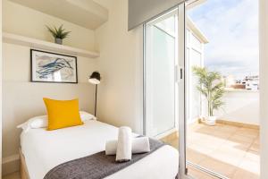 a bedroom with a bed with a yellow pillow and a balcony at Sitges Group Ocean in Sitges